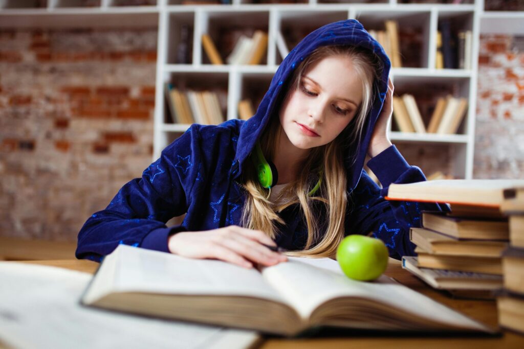 A female student sitting on a chair and reading her book