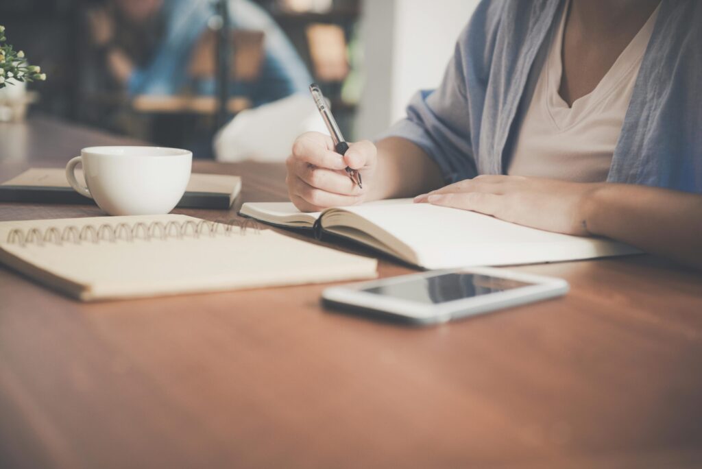 A white lady's handing writing in an open book